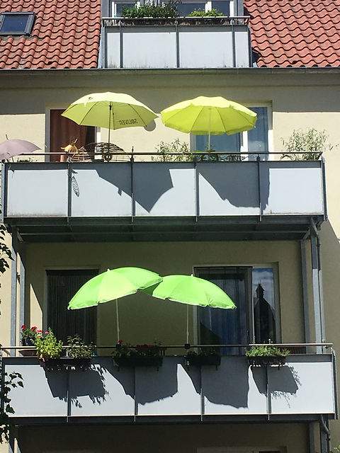 Vier grüne Sonnenschirme auf Balkonen