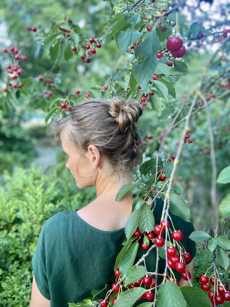 Gartenplanerin Gunhild Rudolph mit geflochtenen Haaren von hinten in einem Sauerkirschbaum