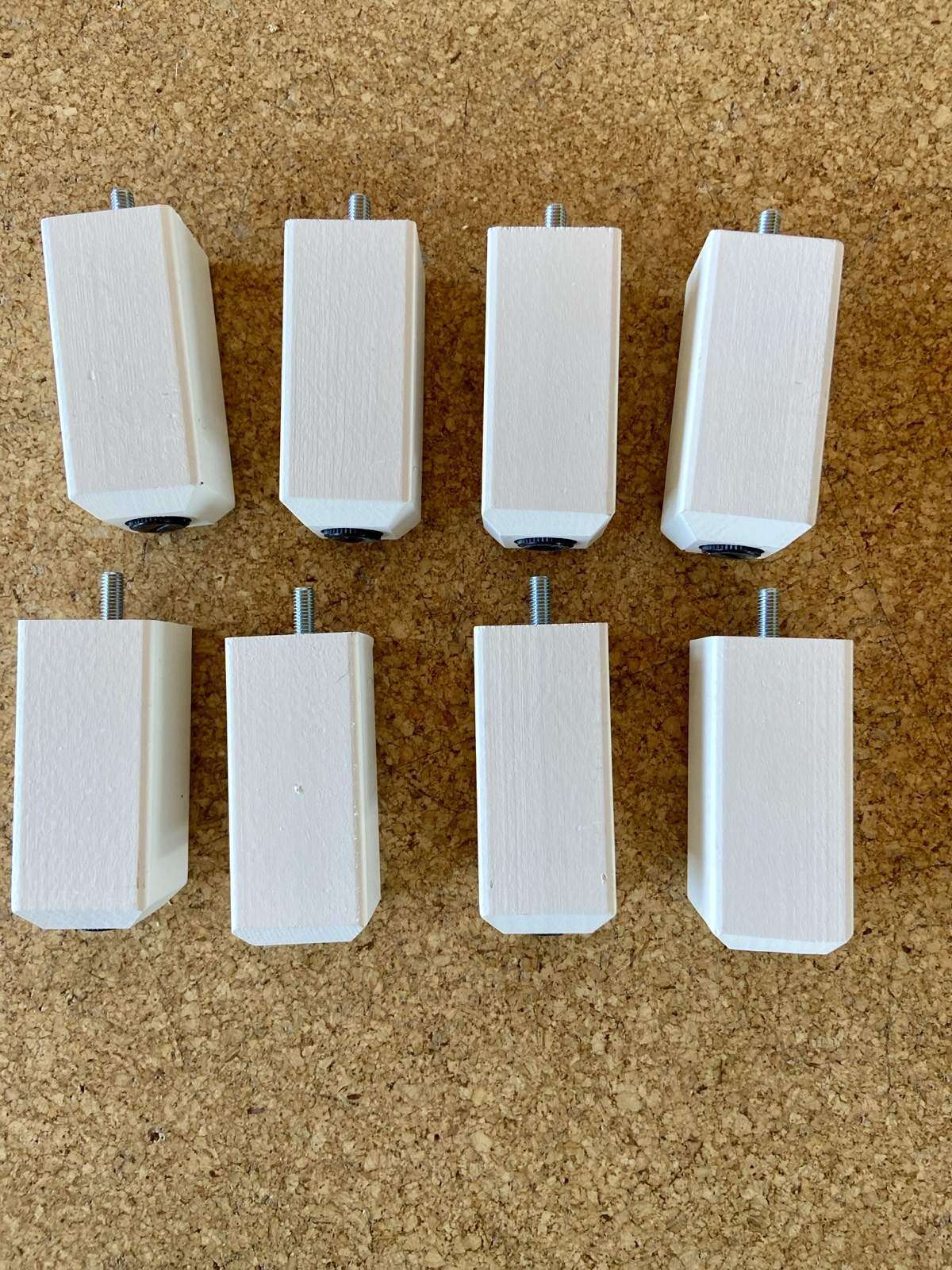 8 weiße IKEA Schrankfüße aus Holz auf Korkboden