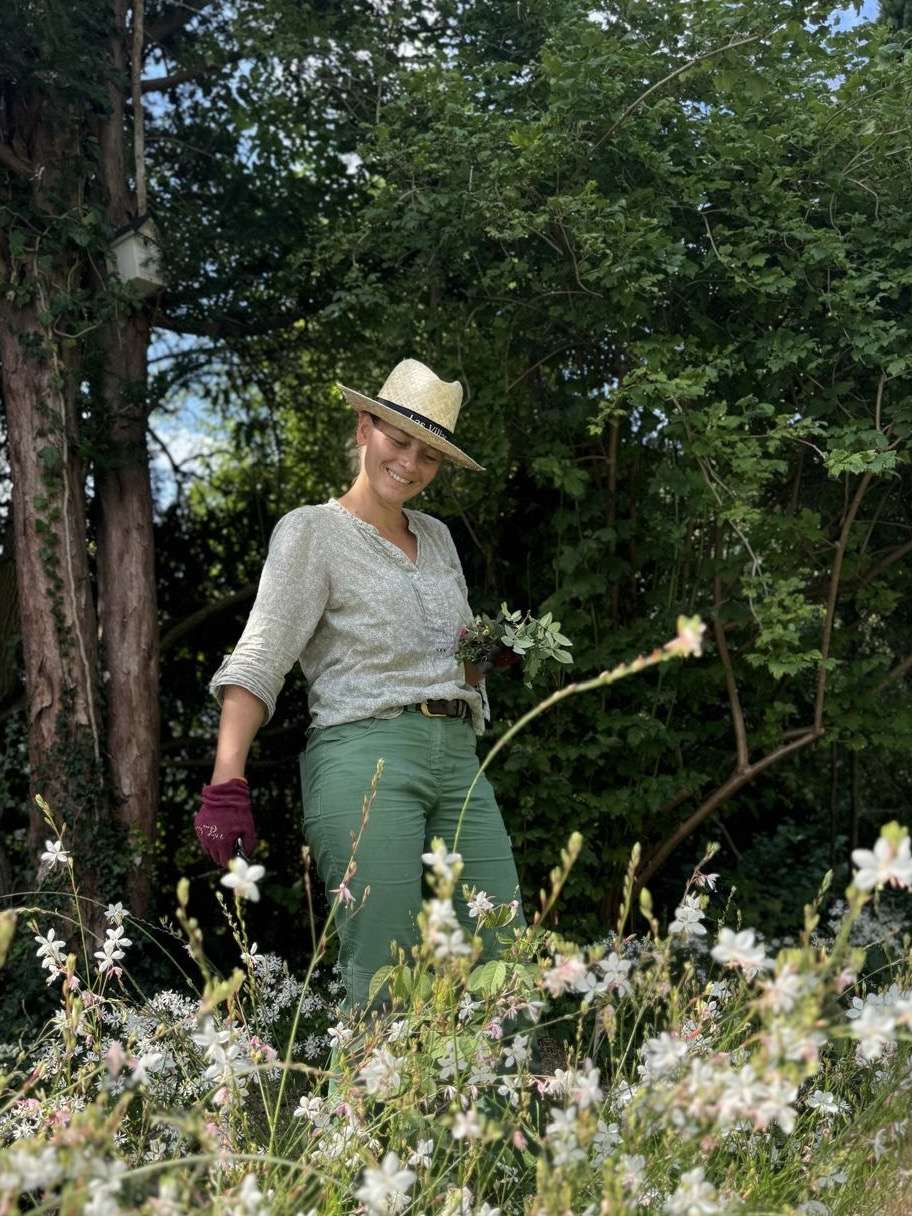 Bloggen für den Garten: Gunhild Rudolph in Gärtnerklamotten hinter weißen Gaura-Pflanzen
