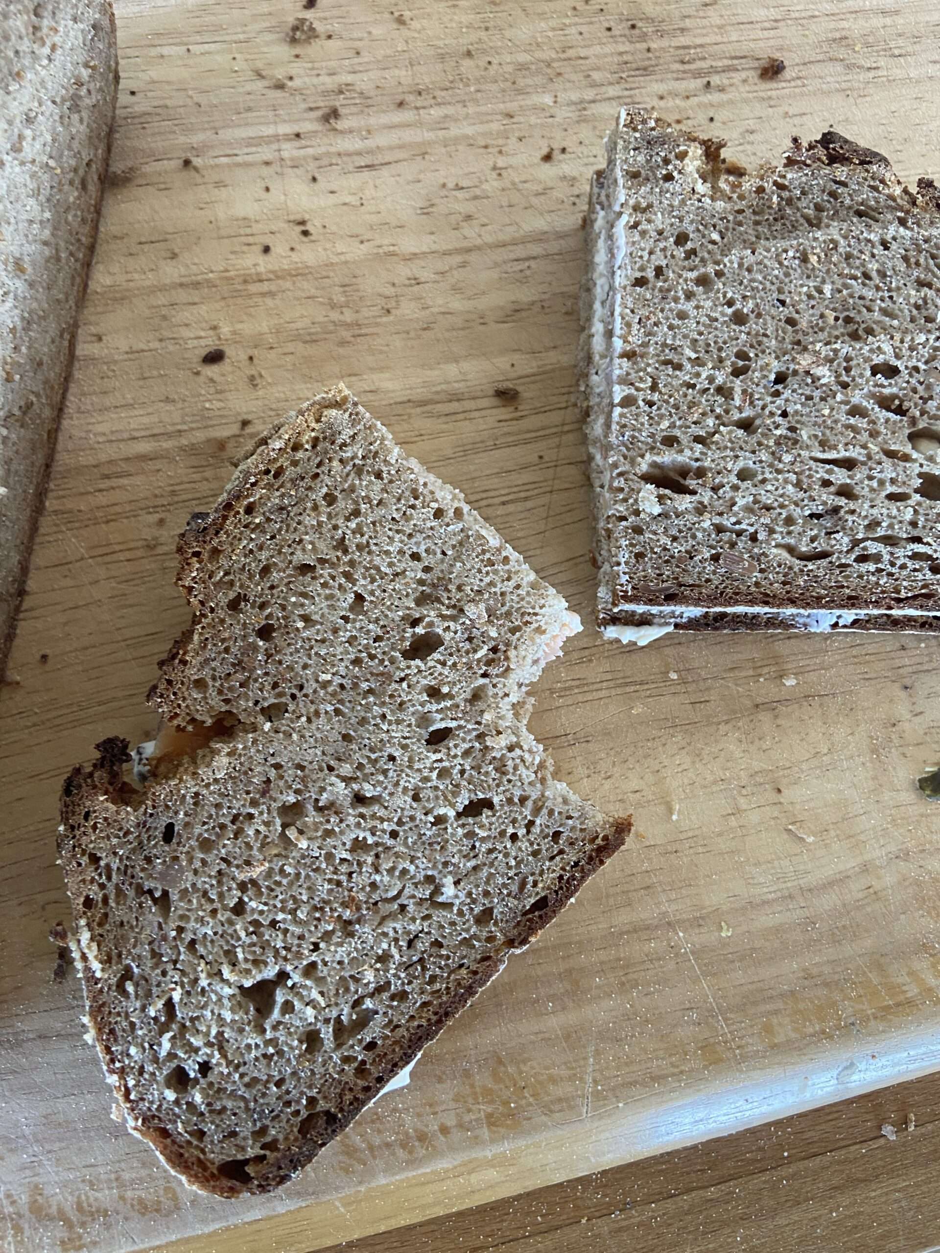 Belegtes Vollkornbrot auf Holzbrett, angebissen