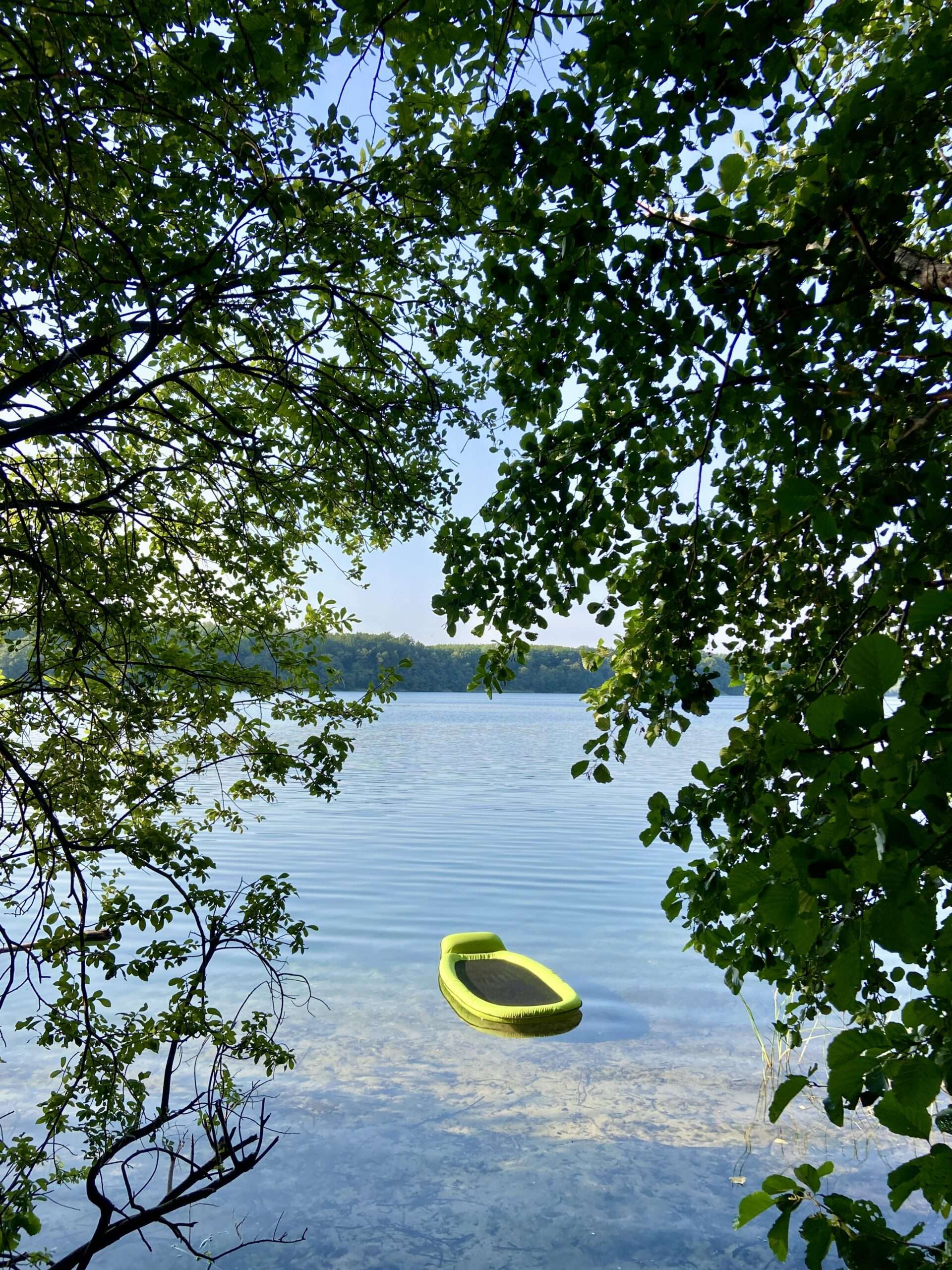 Netzluftmatratze auf dem See, umrahmt von Bäumen