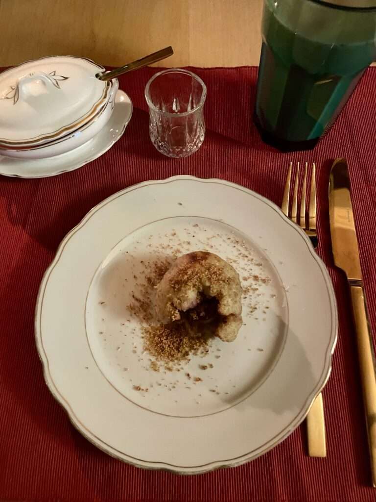 Zwetschgenknödel auf Teller auf rotem Tischset