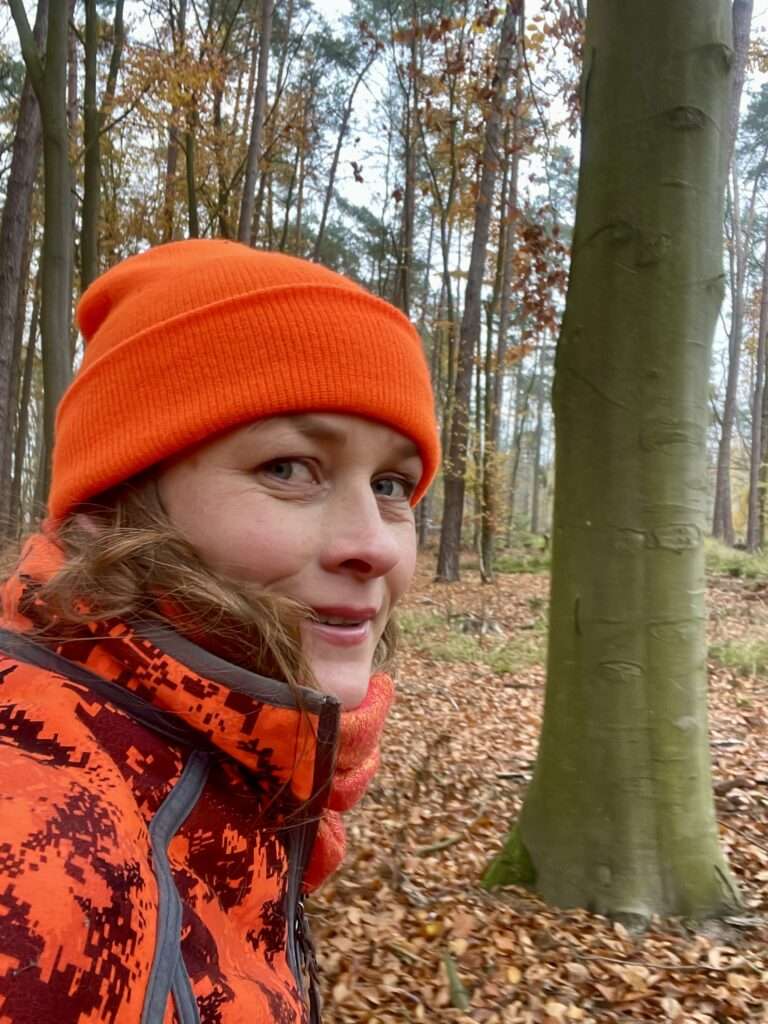 Gunhild Rudolph in orangefarbener Kleidung im Wald