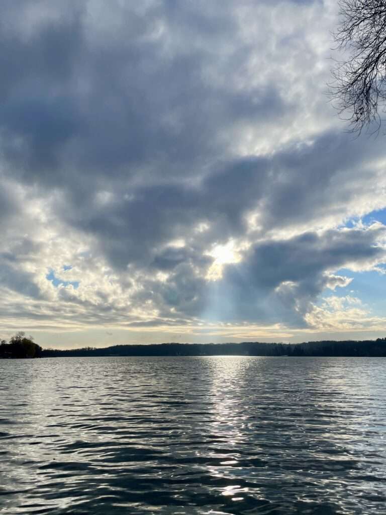 Blick auf einen See mit Sonne hinter den Wolken