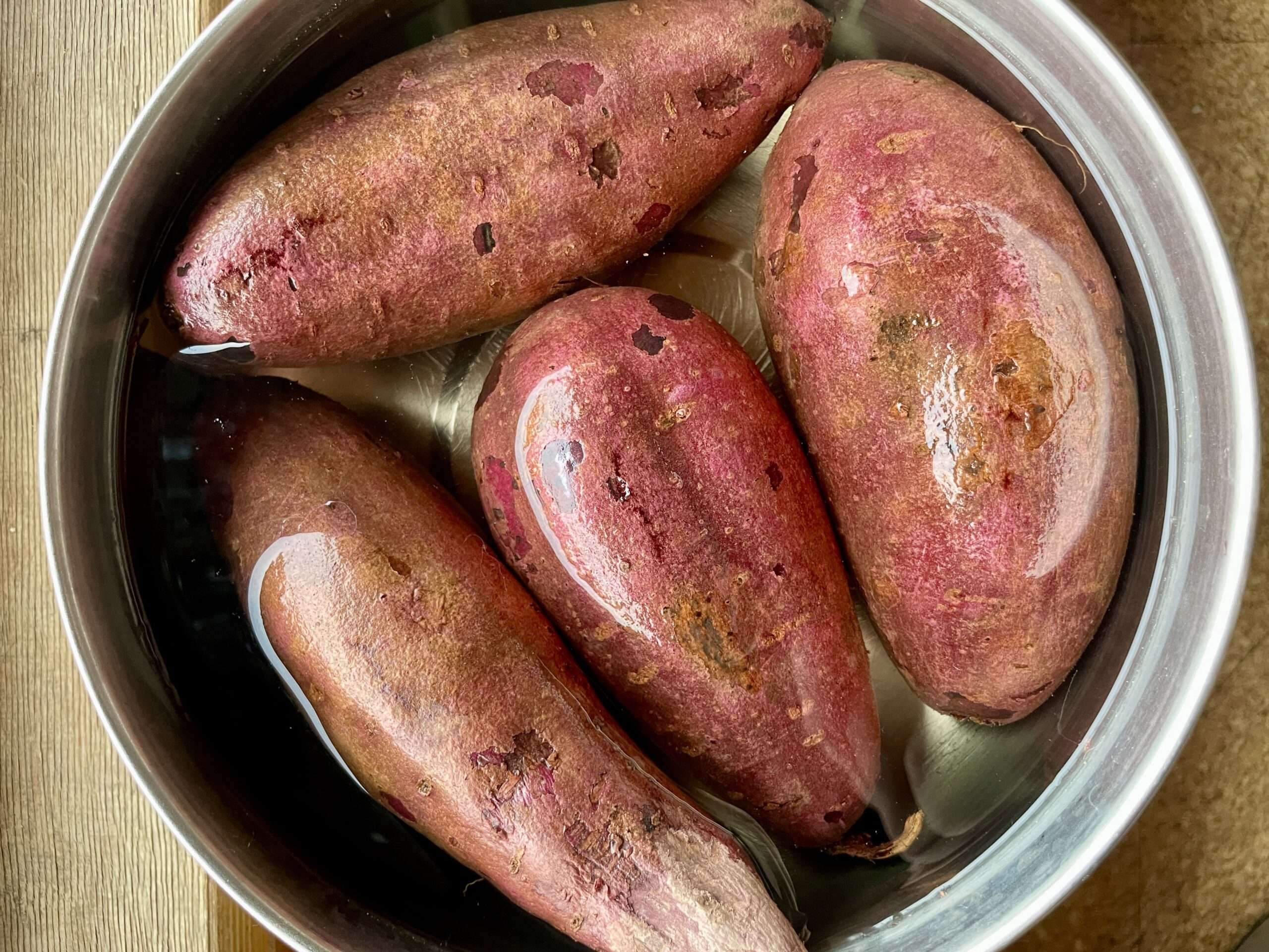 4 Süßkartoffelknollen in einer Wasserschüssel