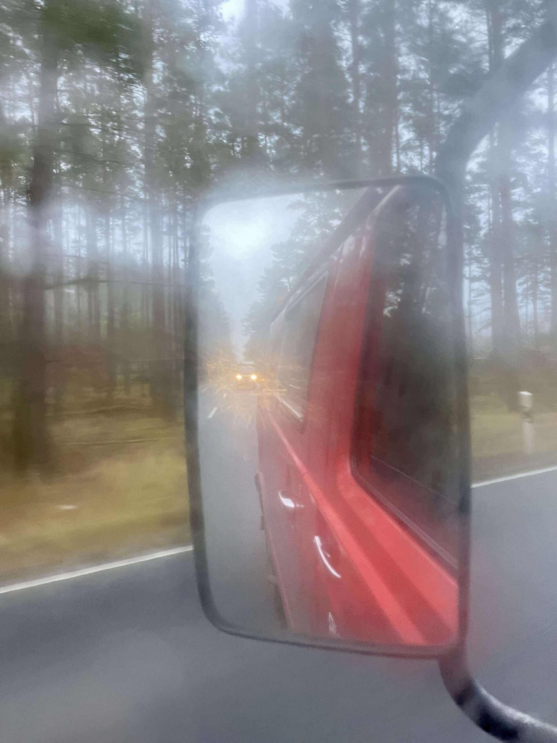 Blick durch die beschlagene Autoscheibe in den Seitenspiegel, in welchem sich durch den Nebel Autoscheinwerfer spiegeln. Von Gunhild Rudolph