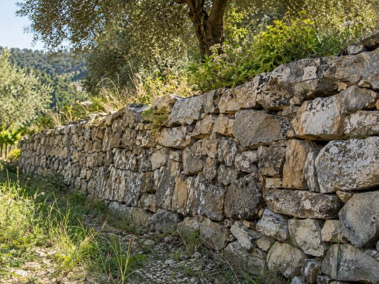 Trockenmauer aus geschichtetem Naturstein an einem Hang